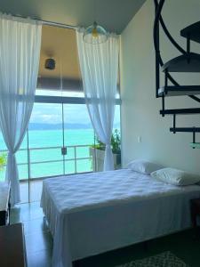 a bedroom with a bed and a large window at Casa pé na areia para até 14 pessoas em bombinhas in Bombinhas