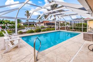 a swimming pool with a white pergola and a white chair at Menorca Court in Marco Island