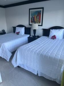two beds in a bedroom with white sheets at Colony Club Inn & Suites in Nassau