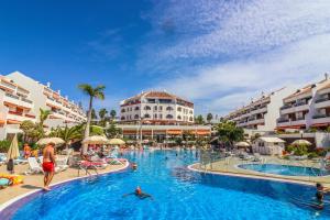 a pool at a resort with people swimming in it at Rentaliday Garden Beach in Playa de las Americas
