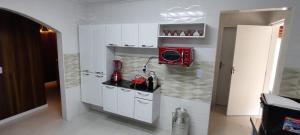 a small kitchen with white cabinets and a red microwave at Casa Campo Bragança in Bragança Paulista
