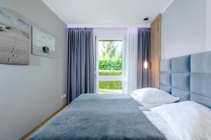 a bedroom with a bed with a blue headboard and a window at Apartament POŁUDNIOWY nad morzem Gardenia Międzywodzie EPapartamenty in Międzywodzie