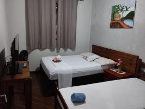 a room with two beds and a tv in it at Pousada Santa Mônica in Divinópolis