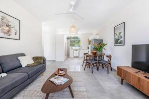 a living room with a couch and a tv and a table at 'Botanica Bonita' A Stylish Nightcliff Hideaway in Darwin +21 photos