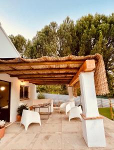 a patio with white chairs and a wooden pergola at Pureza del Hueznar in Cazalla de la Sierra