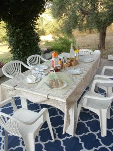 una mesa con sillas blancas y una mesa con comida. en La Casa delle Storie, en Teramo