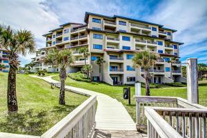 a large apartment building with palm trees and a walkway at 255-56 Sandcastles in Fernandina Beach