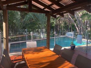 a patio with a wooden table and chairs next to a swimming pool at Ibis 3 House in Rainbow Beach