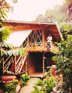 a man standing on the balcony of a wooden house at Hotel Lomas del Paiyü in Puerto Nariño