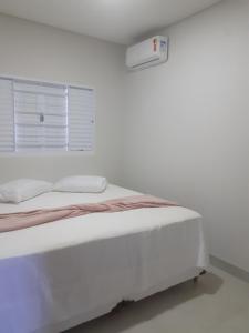 een witte slaapkamer met een bed en een raam bij Casa Nova confortavel e aconchegante 1 in Chapada dos Guimarães
