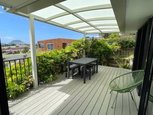 a patio with a table and a chair on a deck at Habour View - Tauranga Central in Tauranga