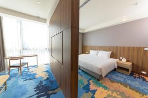 a bedroom with a bed and a desk and a table at JANDA Golden Tulip Hotel in Wuqi