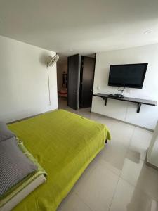a bedroom with a green bed and a flat screen tv at Apartamento Amoblado Villeta in Villeta