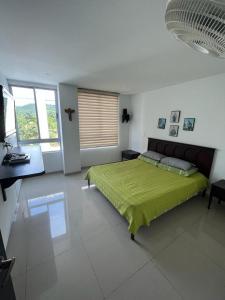 a bedroom with a bed with a green blanket at Apartamento Amoblado Villeta in Villeta