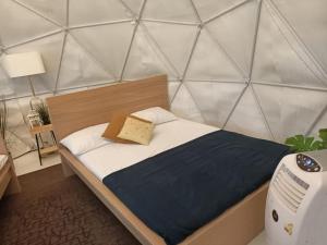 ein kleines Bett in einem Zimmer mit einer Wand in der Unterkunft Seaside Glamping@Heritage Chalet in Singapur