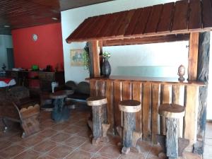 a bar with wooden stools in a room at Pousada Por Do Sol chalés in Monte Verde