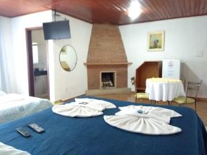 a room with two towels on a bed with a fireplace at Pousada Por Do Sol chalés in Monte Verde