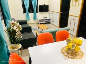 a living room with a white table and orange chairs at Airport View Homestay Kuala Terengganu in Kuala Terengganu