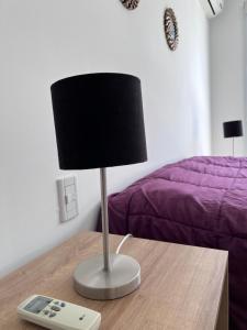 a lamp sitting on a table with a remote control at SAN LUIS CENTRO Departamento monoambiente in San Luis