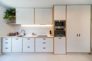 cocina con armarios blancos y microondas en Remarkable Studio in convenient Frankton en Frankton Wharf