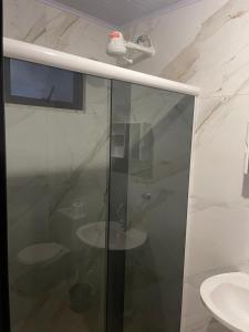 a glass shower in a bathroom with two sinks at Itapema Suítes in Itapema