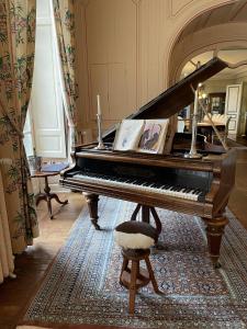 a piano sitting in a room with a chair at Chateau La Rametiere in Plomb
