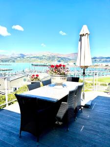 a table and chairs on a deck with an umbrella at Sea views in luxury at LYTTELTON BOATIQUE HOUSE - 14 km from Christchurch in  Lyttelton