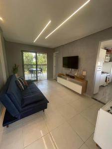 a living room with a blue couch and a kitchen at Apartamento na Praia do Francês in Praia do Frances