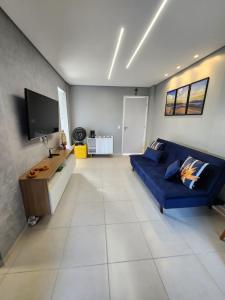 a living room with a blue couch and a tv at Apartamento na Praia do Francês in Praia do Frances