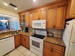 una cocina con armarios de madera y electrodomésticos blancos en Summerhouse 251 Condo, en St. Augustine