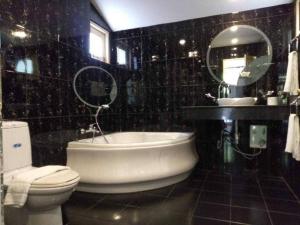 y baño con bañera, aseo y espejo. en Private Pattaya Resort en Nong Prue