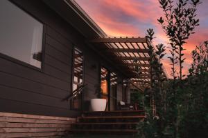 a house with a potted plant on the side of it at Koa Cabin Hahei in Hahei