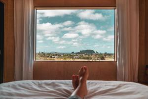 a person laying on a bed looking out a window at Koa Cabin Hahei in Hahei