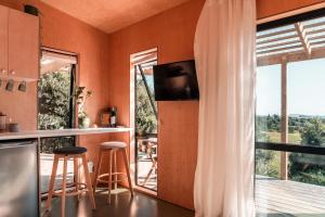 a kitchen with orange walls and a large window at Koa Cabin Hahei in Hahei