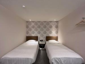 two beds in a room with white walls at Hotel Puri in Taipei