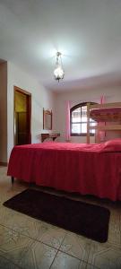 um quarto com uma cama grande e um cobertor vermelho em Chácara Sorriso 2 em Atibaia