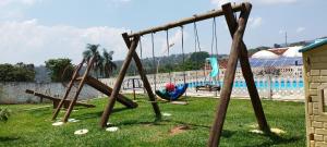 a group of swings in a park next to a pool at Chácara Sorriso 2 in Atibaia