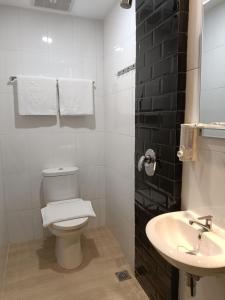 a white bathroom with a toilet and a sink at Odua Golden Mansyur Medan in Medan
