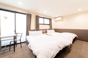 two beds in a room with a desk and window at Le Studio 五条高倉 in Kyoto