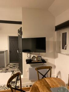 een woonkamer met een tafel en een tv aan de muur bij La tête dans les étoiles in Aumont