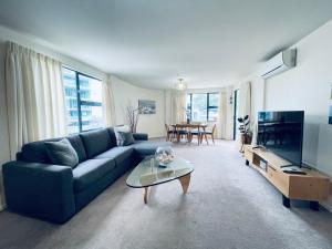 a living room with a blue couch and a tv at Oceanside Apartment in Mount Maunganui