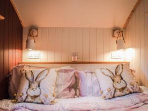 two rabbits are sitting on a bed with pillows at Little Willows in Potterne