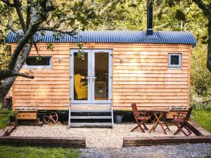 a tiny house with a door and a table and chairs at Little Willows in Potterne