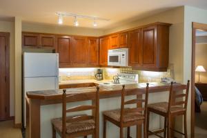 a kitchen with a white refrigerator and wooden cabinets at 3219 - Three Bedroom Standard Powderhorn Lodge condo in Solitude