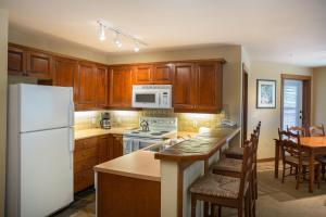 a kitchen with wooden cabinets and a white refrigerator at 3219 - Three Bedroom Standard Powderhorn Lodge condo in Solitude +15 photos
