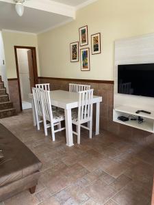 ボンビーニャスにあるDuplex Costa Esmeraldaのダイニングルーム(白いテーブル、椅子、テレビ付)