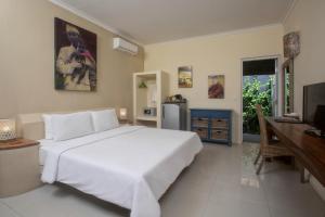 a bedroom with a large white bed and a desk at Scallywags Mango in Gili Air