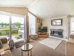 a living room with a couch and a tv at Links Lodge in Grange Over Sands