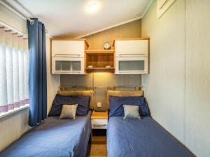 two beds in a small room with blue sheets at Links Lodge in Grange Over Sands
