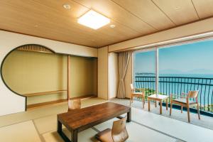 Habitación con mesa, sillas y balcón. en KAMENOI HOTEL Genkainada en Kitakyushu